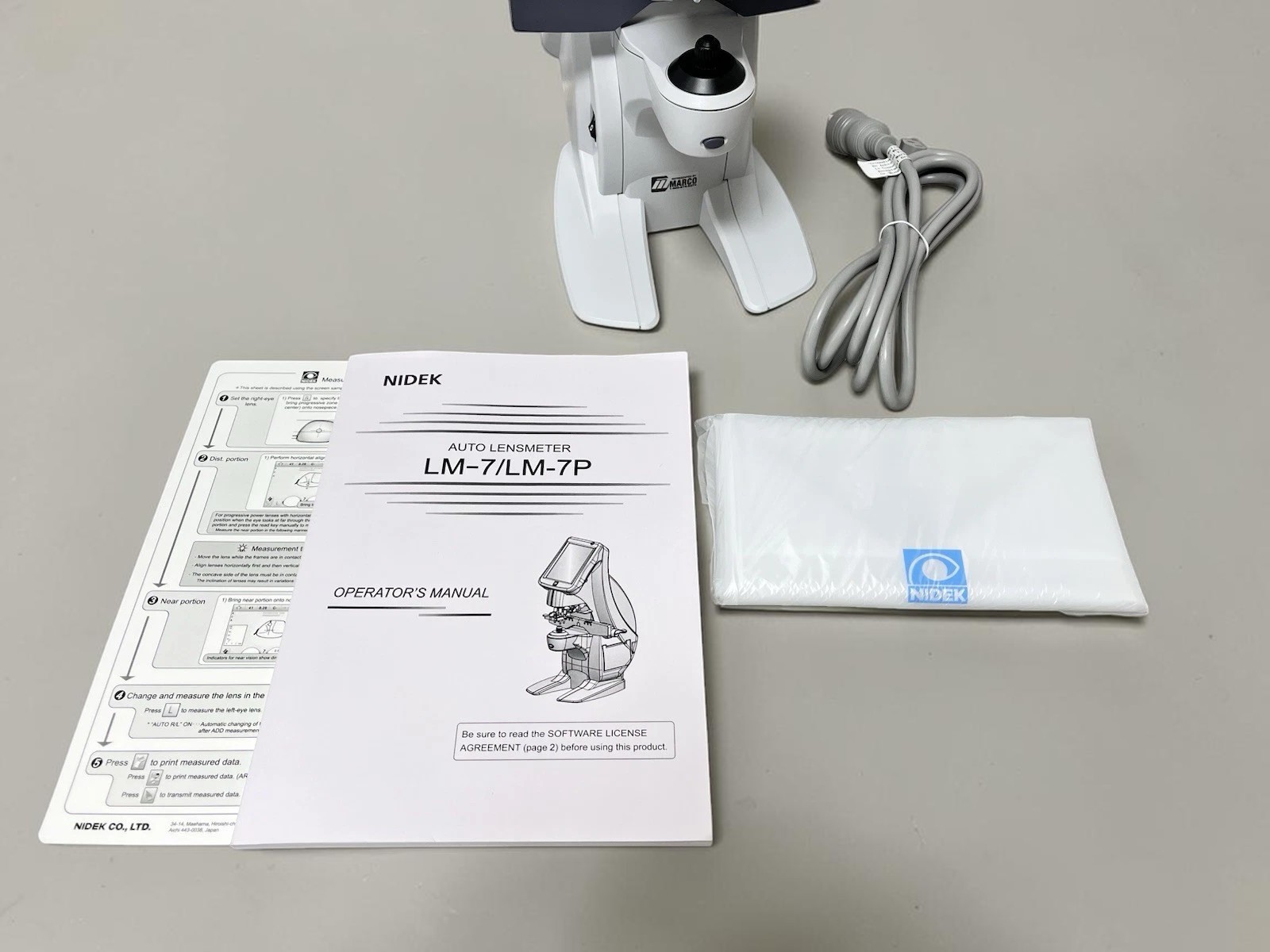 Nidek LM-7 - Auto Lensmeter - Used 2 Nidek LM-7 auto lensmeter used — angled view of lens table and included accessories
